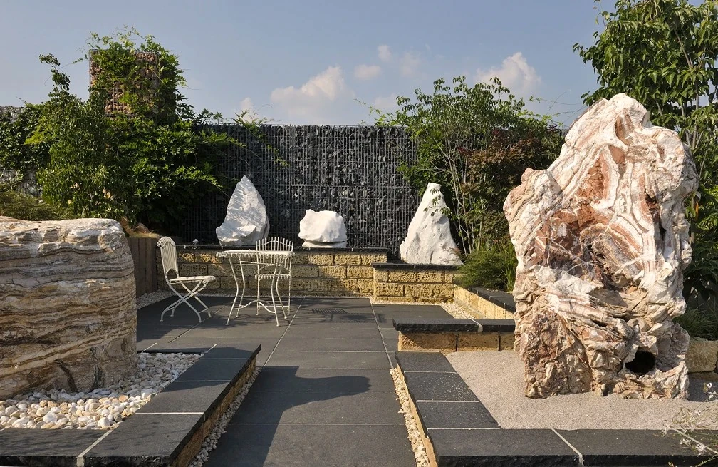 Naturalny monolit kamienny jako rzeźba ogrodowa przy tarasie z czarnego wapienia.webp